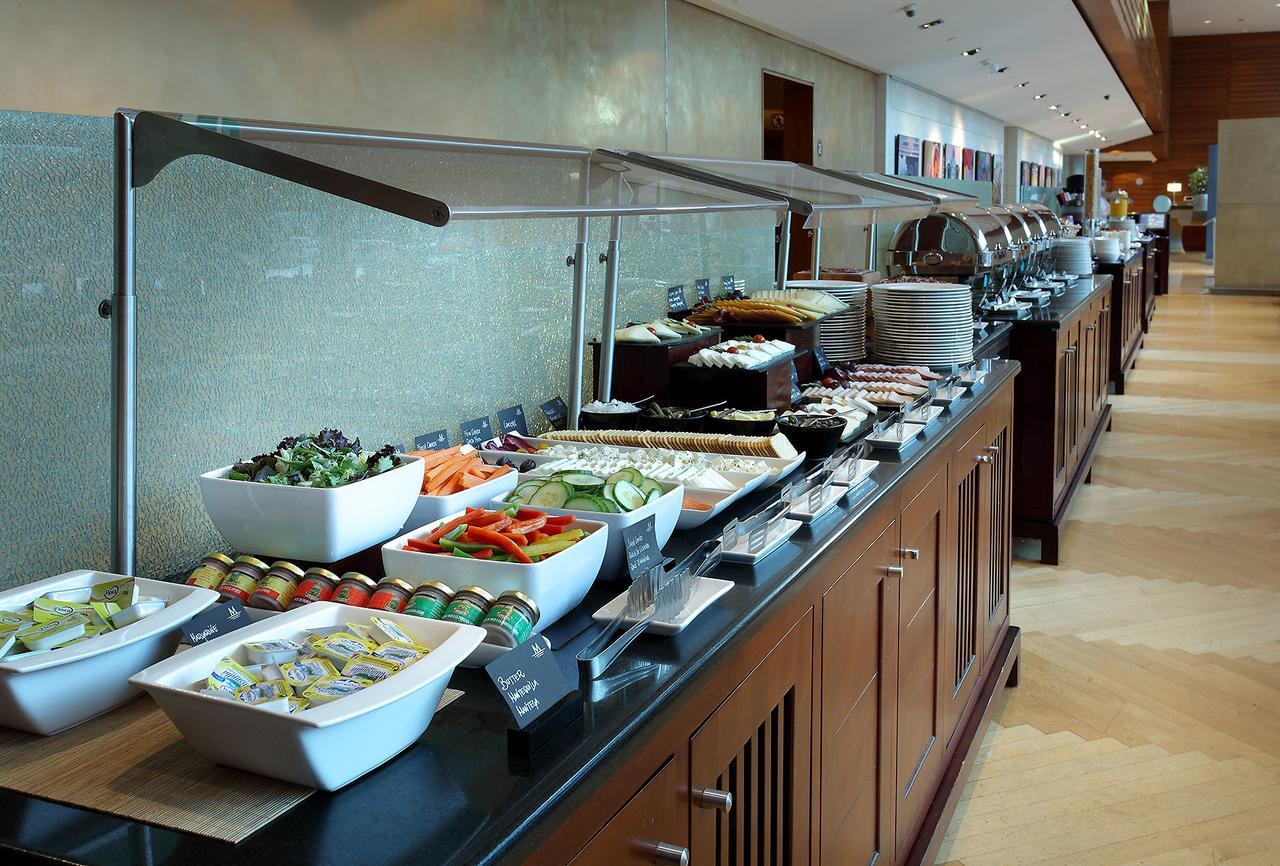 Eurostars Grand Marina Hotel GL Barcelona Exterior foto The photo shows a buffet spread featuring a variety of dishes arranged along a long serving counter. There are several bowls and platters containing fresh salads, sliced vegetables, and other food items. The setting appears modern and well-organized,